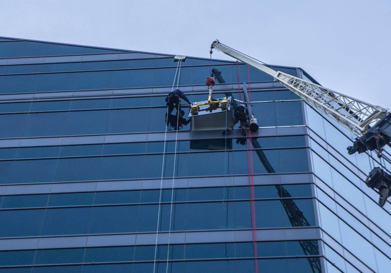 A group of people hanging from a crane on the side of a building.